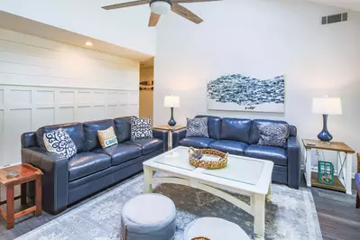 The living room features shiplap walls, a large seating area and vaulted ceilings.