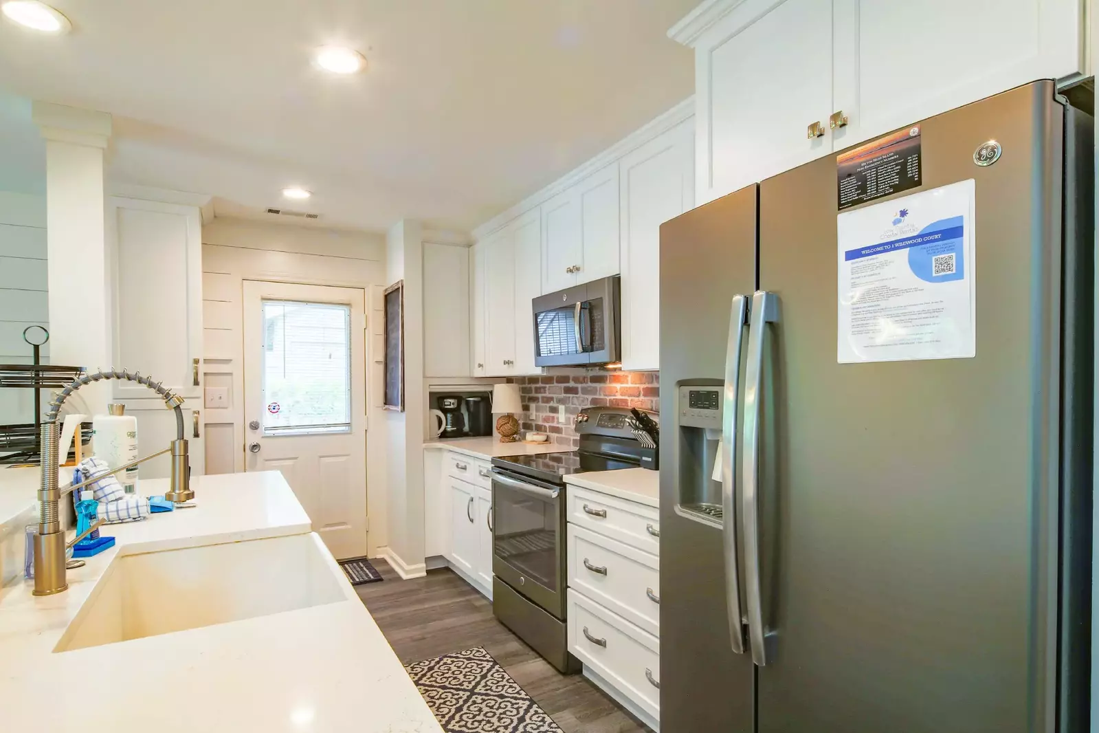 This beautiful kitchen features stainless steel applainces, white cabinetry and a brick backsplash.