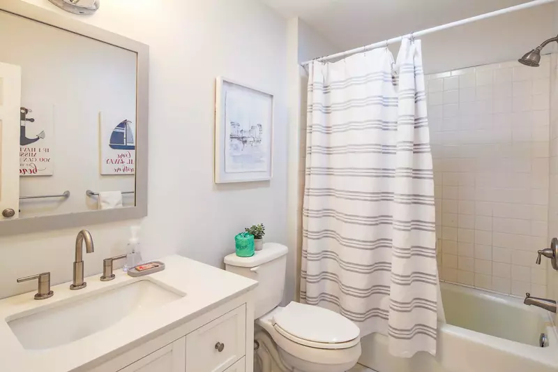 This hallway bathroom features a spacious vanity and a shower/tub combo.