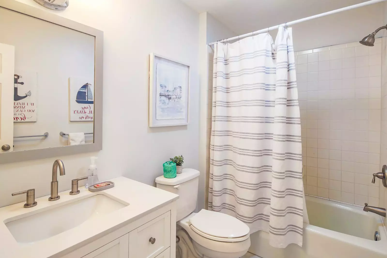This hallway bathroom features a spacious vanity and a shower/tub combo.