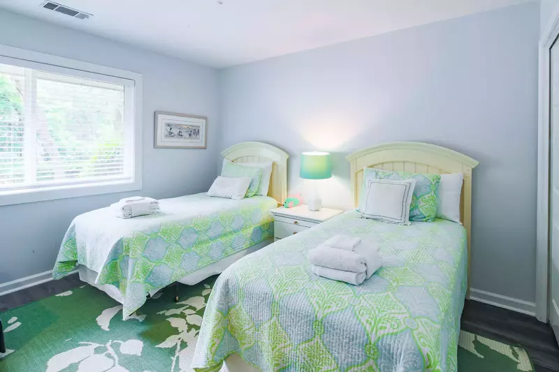 The twin guest bedroom features two twin beds and a night stand with a reading lamp.