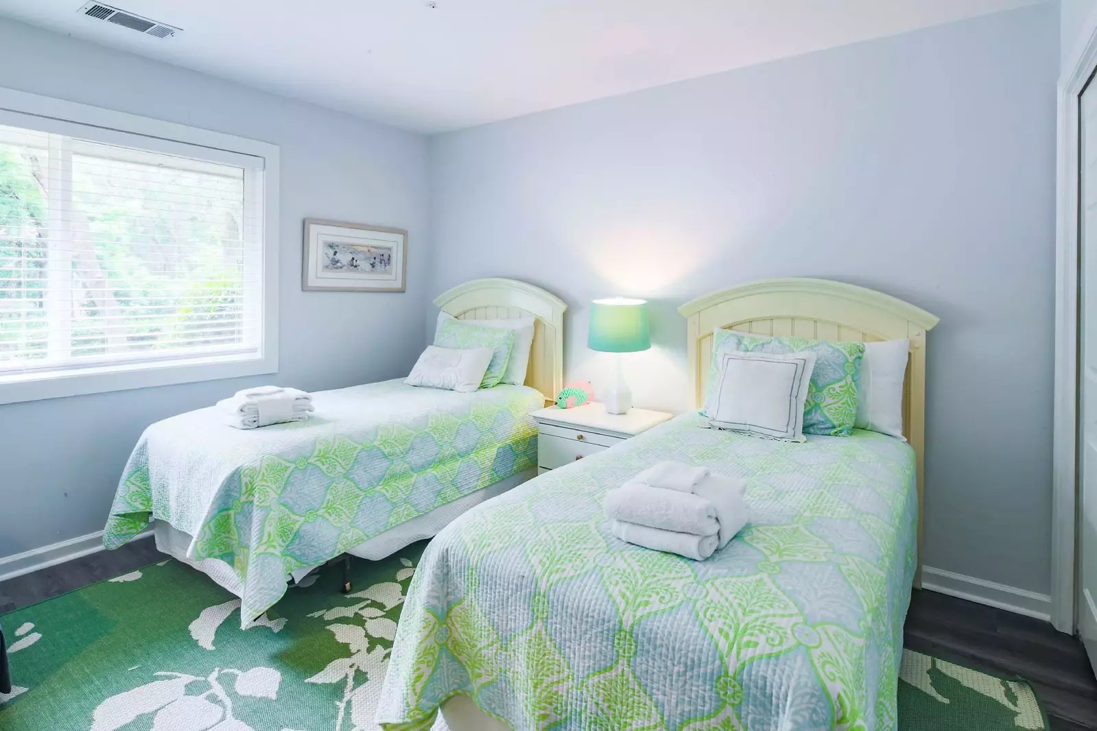 The twin guest bedroom features two twin beds and a night stand with a reading lamp.