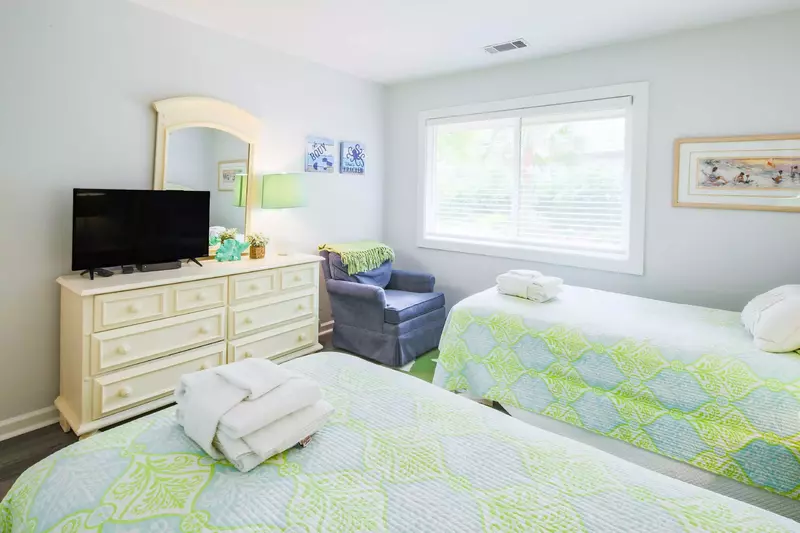 The twin guest bedroom also features a dresser, flat screen TV and an arm chair.