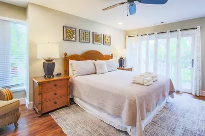 The master suite features a king bed, night stands with reading lamps and sliding door access to the exterior balcony.