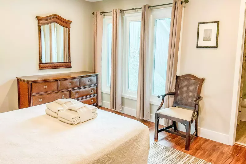 The queen suite also features a dresser, ceiling fan and arm chair.