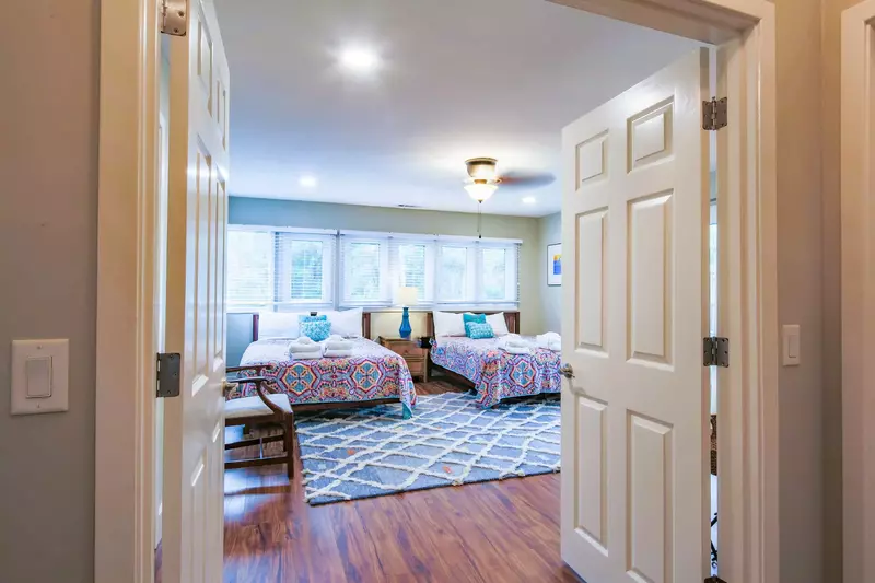 The guest bedroom features two queen beds, night stand with reading lamp and an arm chair.