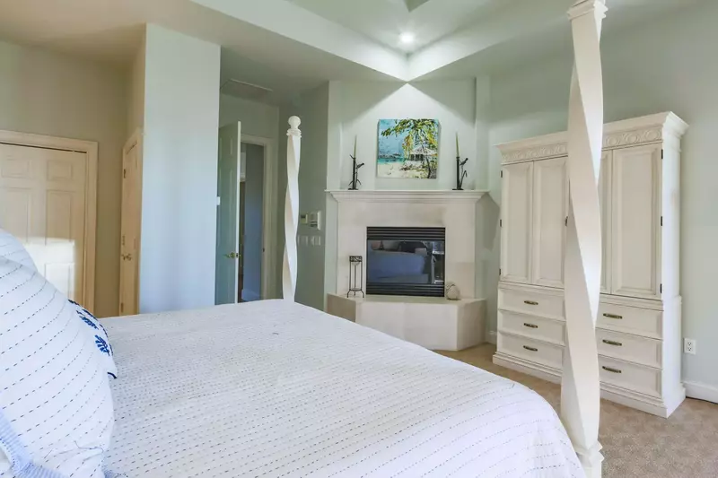 The master suite features vaulted ceilings, an armoire and a king bed.