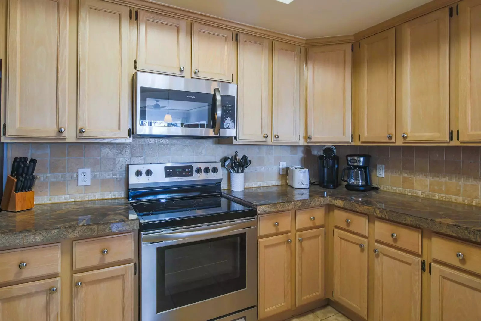 The kitchen features stainless steel appliances, honey cabinets and granite counters.