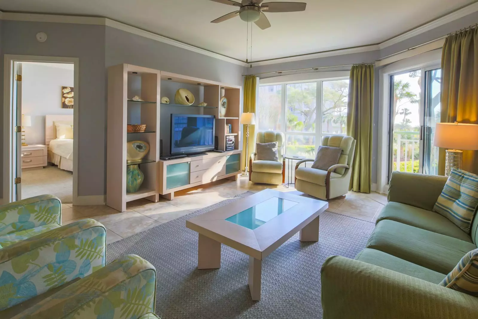 The comfortable living room features a large seating area, flat screen TV and sliding door access to a covered balcony.
