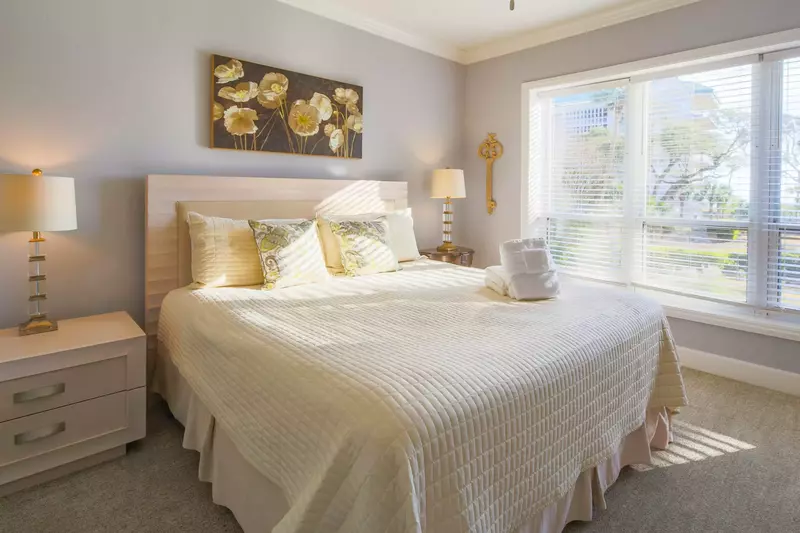 The master suite features lovely natural light, a king bed and night stands with reading lamps.
