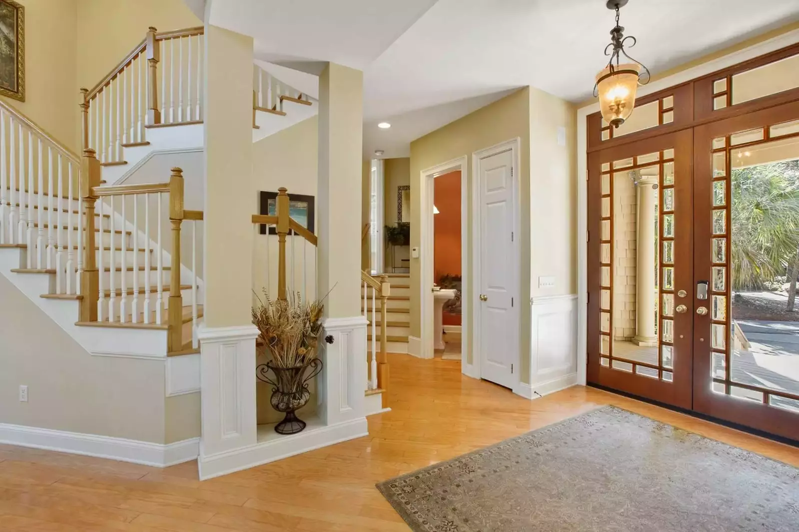 The hallway near the front door leads to the stairwell to the second floor, a half bathroom and the stairs to the master suite.