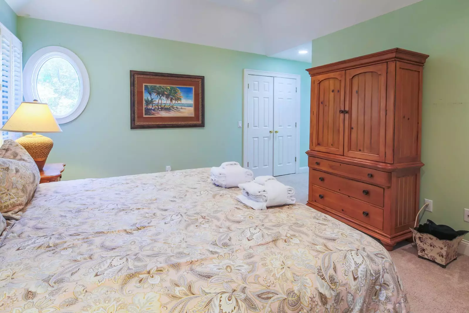 The en suite bathroom is down the small hallway near the armoire.