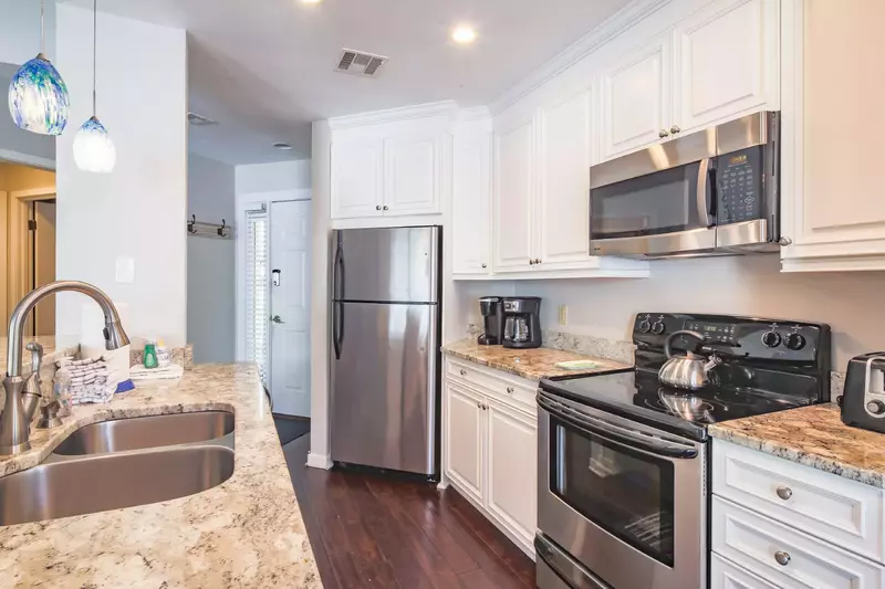 The kitchen features stainless steel appliances and wood floors.