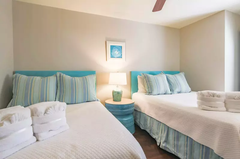 The guest bedroom features a queen bed, a full bed and a night stand with a reading lamp.