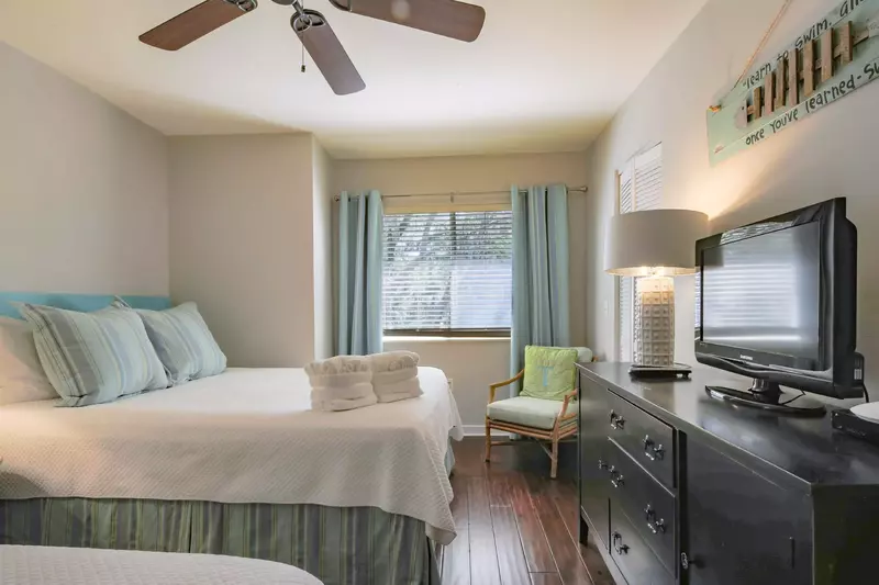 The queen bedroom also has a dresser, flat screen TV, arm chair and ceiling fan.
