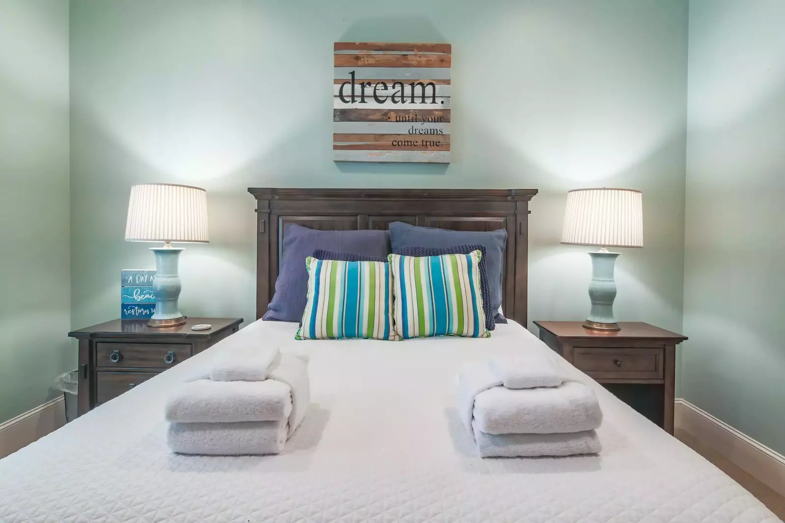 There is a nightstand with reading lamp on both sides of the queen bed.