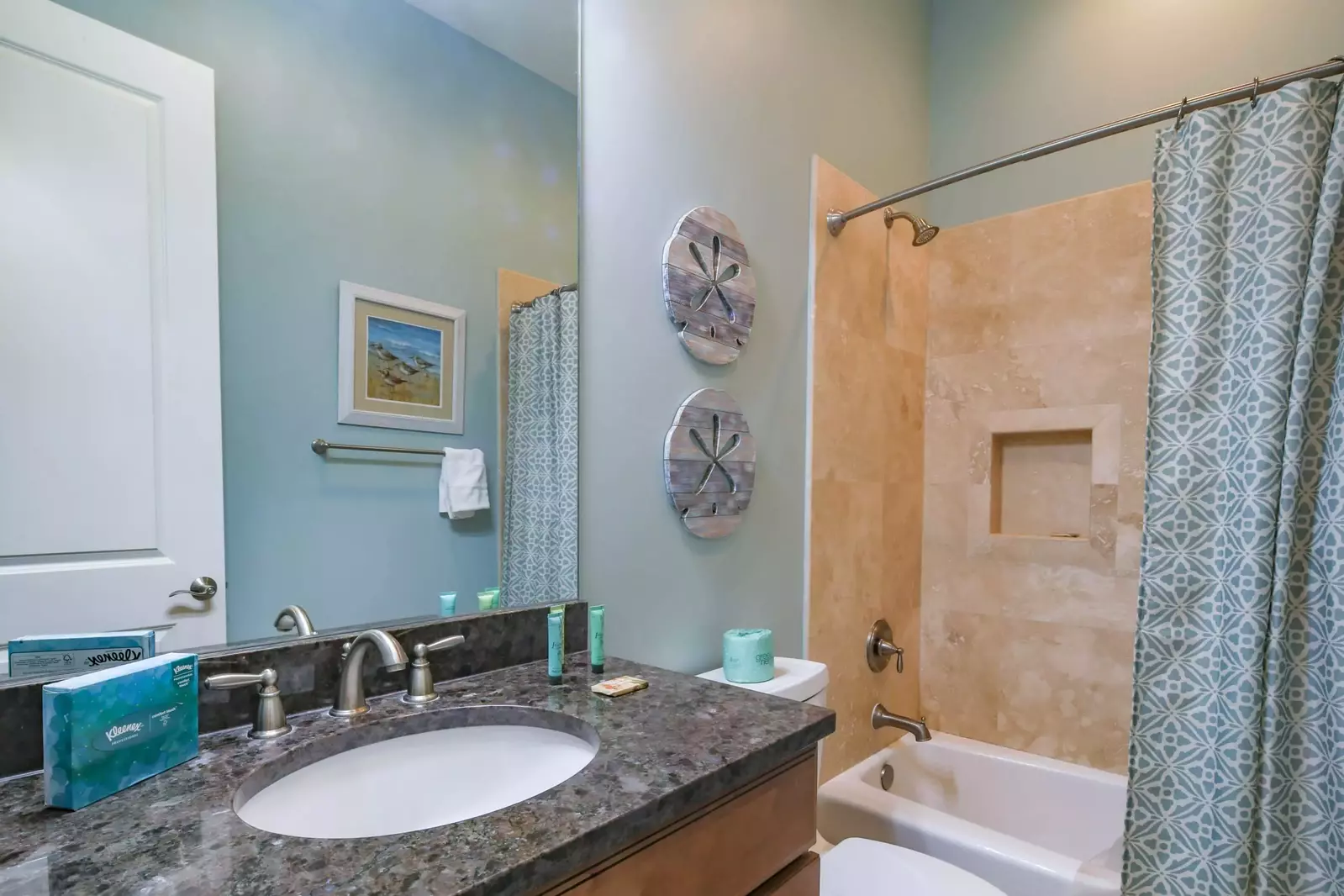 This hallway bathroom features a vanity and shower/tub combo.