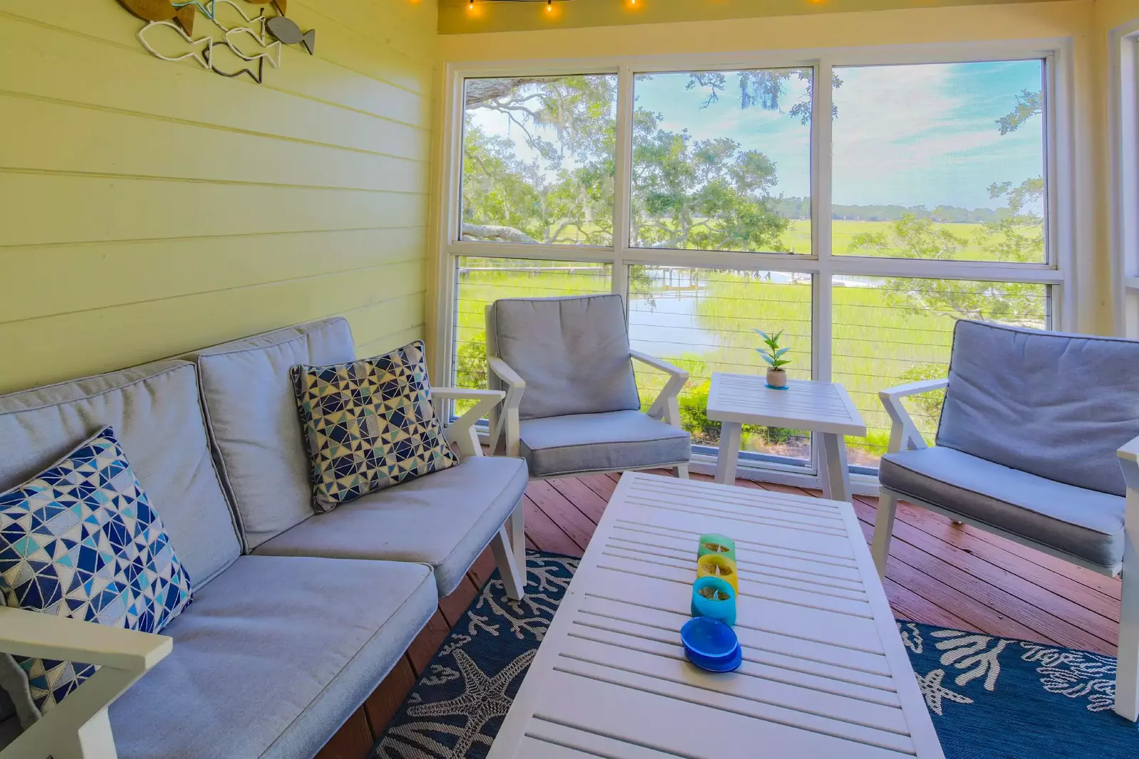 The screened porch features a comfortable seating area and stunning marsh views.