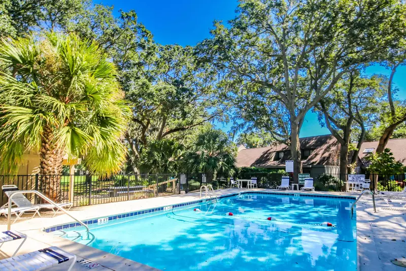 The community pool features lounge chairs, a sundeck and beautiful landscaping.