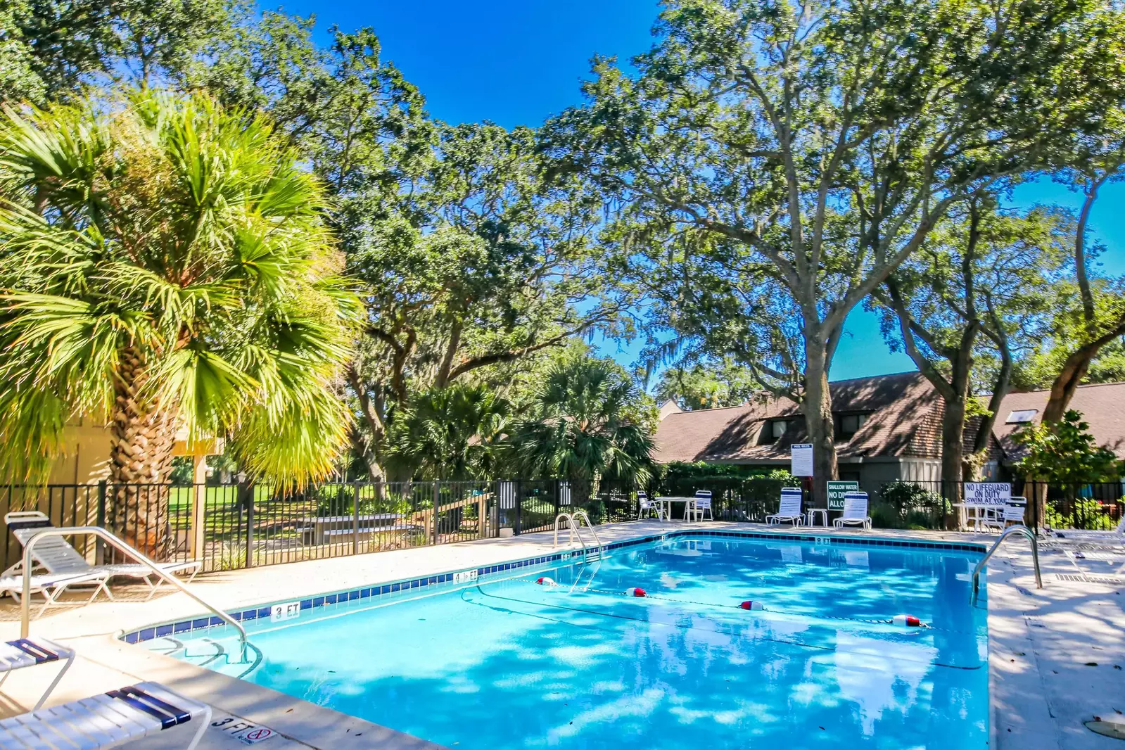The community pool features lounge chairs, a sundeck and beautiful landscaping.