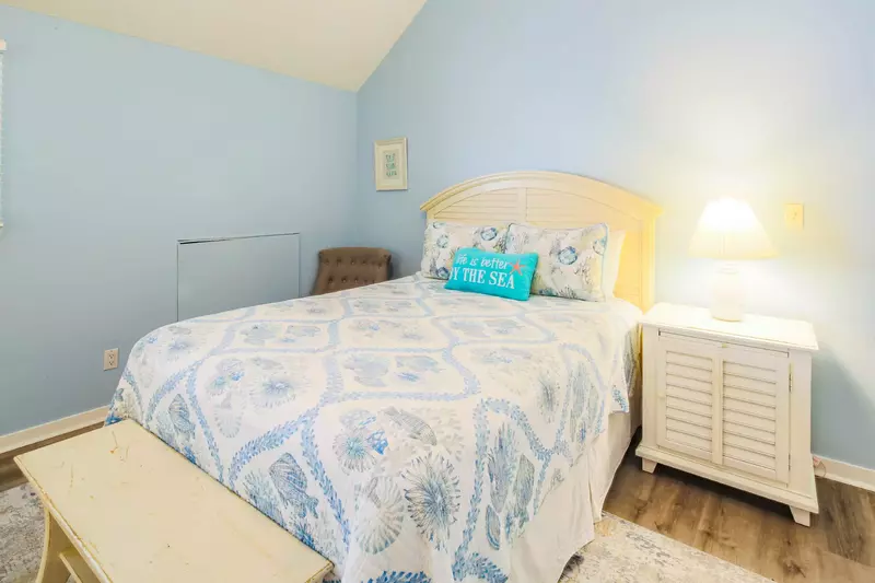 The queen bedroom features a queen bed, bench and a night stand with a reading lamp.
