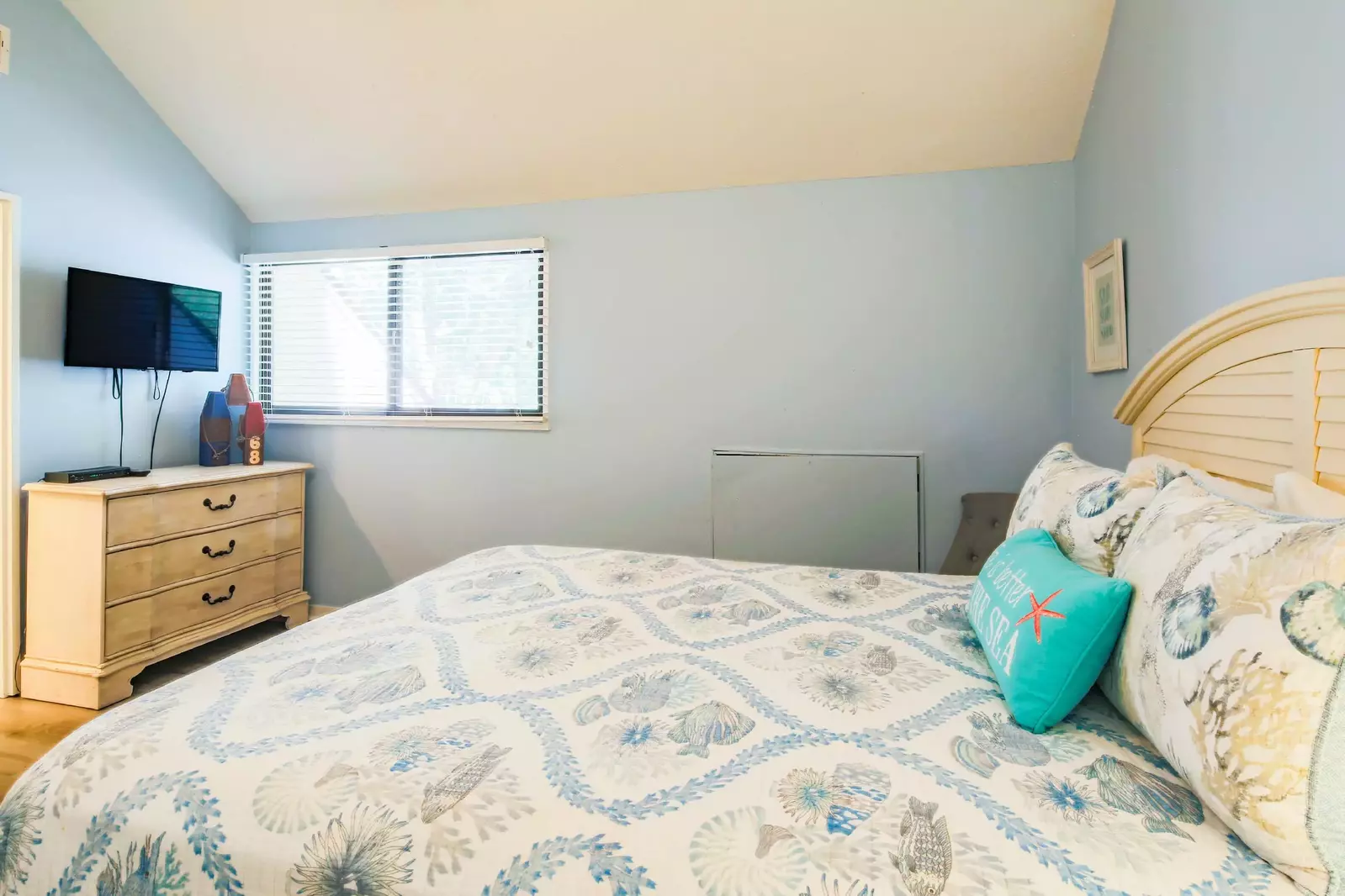 The queen bedroom also has a dresser and wall-mounted TV.