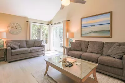 The bright & sunny living room features vaulted ceilings and sliding door access to the back deck.