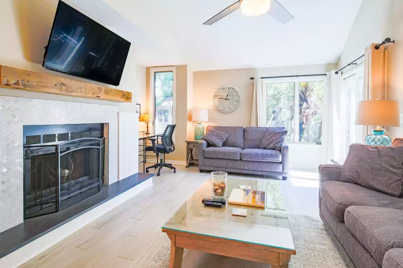 The living room features a wall-mounted smart TV, vaulted ceilings and queen sleeper sofa.  Fireplace not available for guest use.