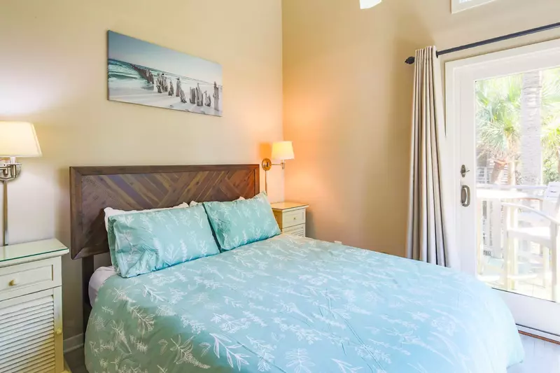 The bedroom features a queen bed with night stands and wall sconces.