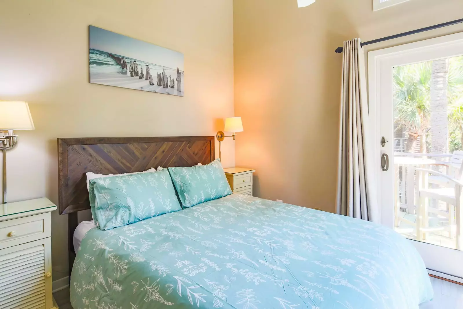 The bedroom features a queen bed with night stands and wall sconces.
