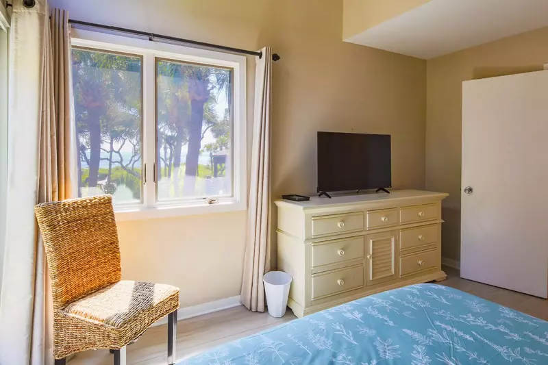 The bedroom also features ocean views, a dresser with a smart TV and a chair.