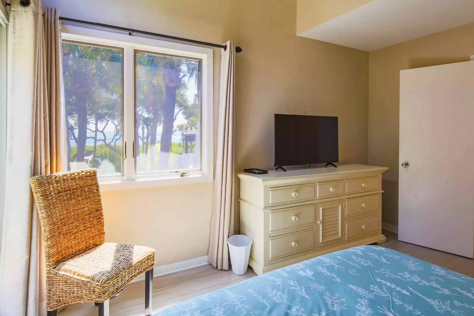 The bedroom also features ocean views, a dresser with a smart TV and a chair.