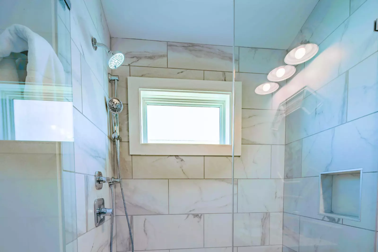 The master bathroom features a tiled, walk-in shower with two shower heads.