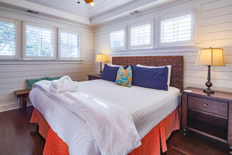 The master suite, located on the 2nd floor, has shiplap walls, a king bed and night stands with reading lamps.