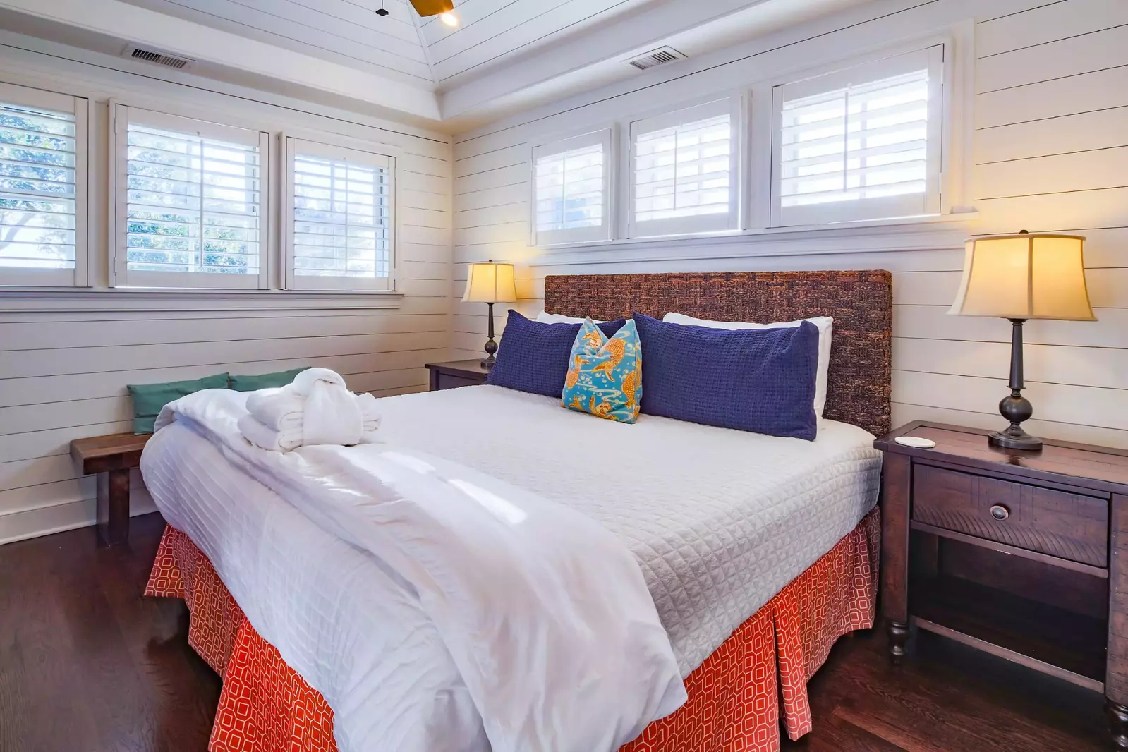 The master suite, located on the 2nd floor, has shiplap walls, a king bed and night stands with reading lamps.