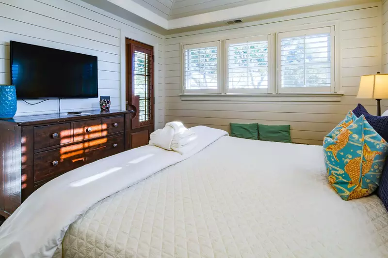 The master suite also has access to the covered porch, a dresser and mounted smart TV.