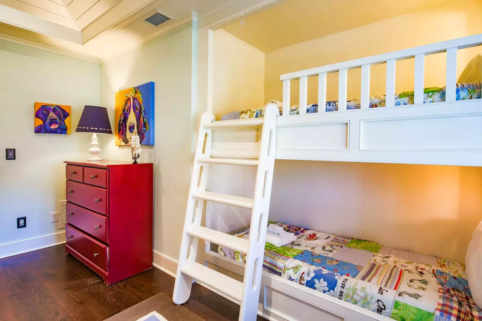 The bunk room also features a dresser and fun, brightly colored artwork.