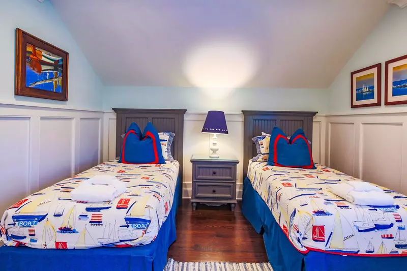 This upper level bedroom features two twin beds and a night stand with a reading lamp.
