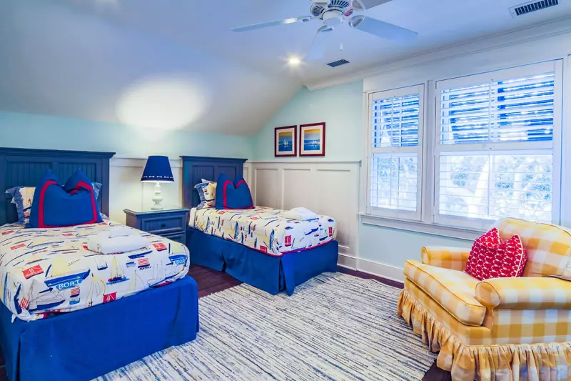 This guest bedroom also has an arm chair and a ceiling fan.