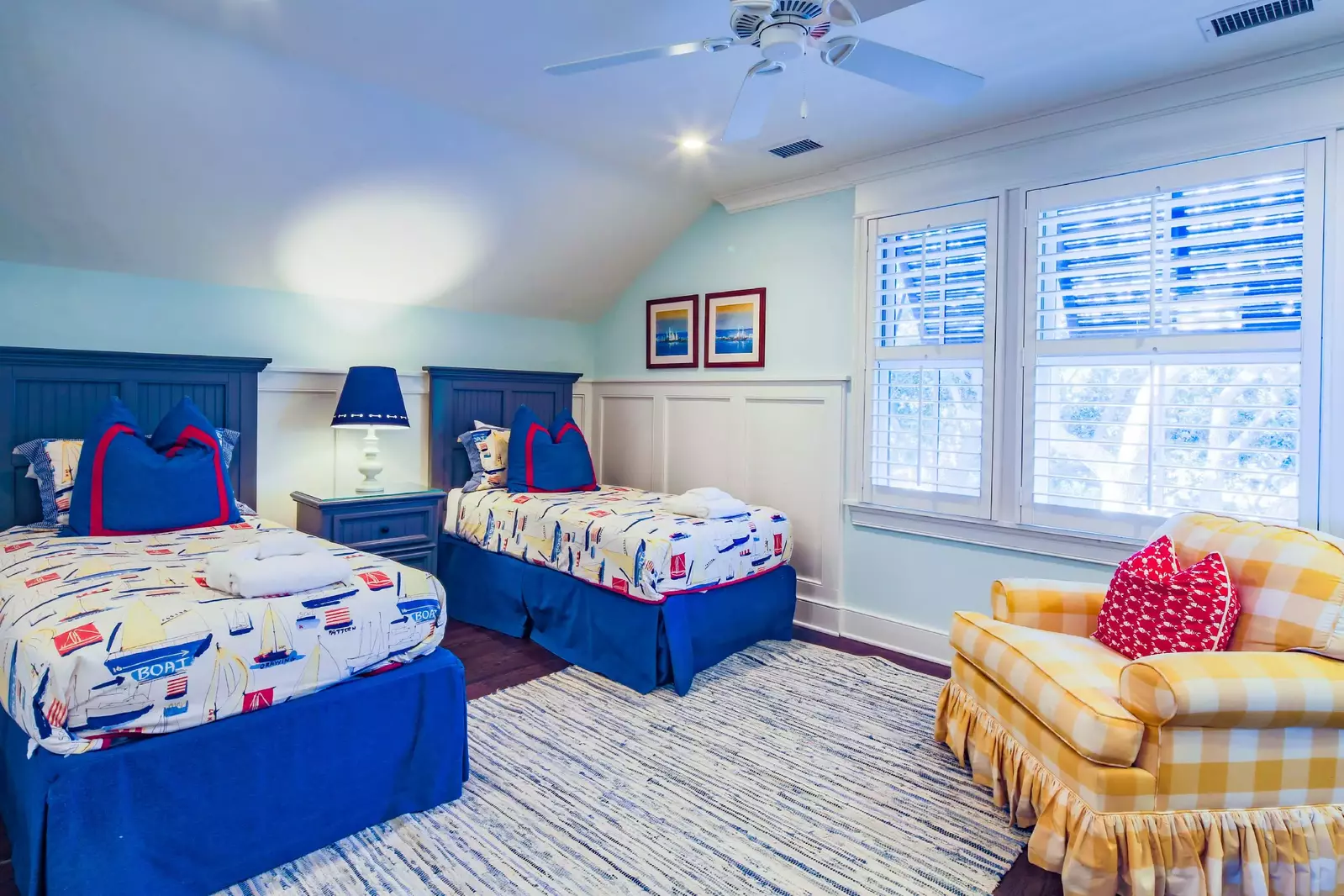 This guest bedroom also has an arm chair and a ceiling fan.