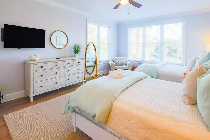 This guest bedroom has a dresser, arm chair and wall-mounted streaming TV.