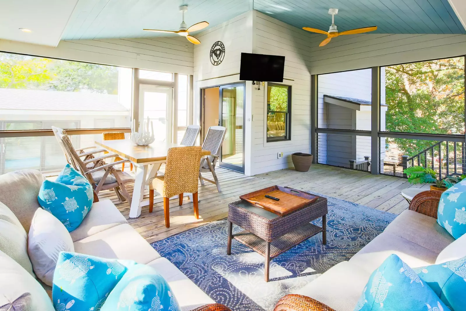 The bright & airy screened porch features a seating area, wall-mounted TV and dining table & chairs.