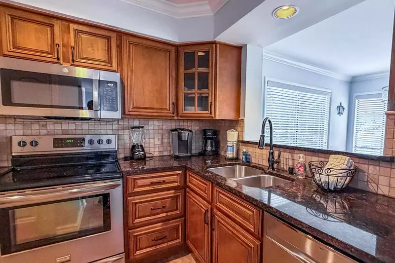 The renovated kitchen features granite counters, brown cabinets and a tiled backsplash.