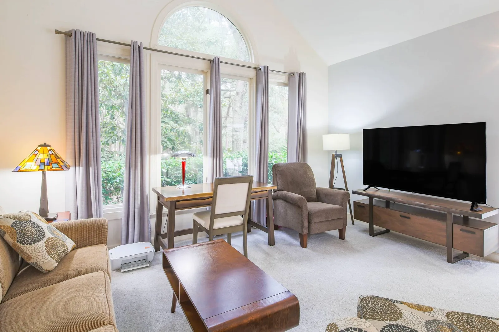 The den features a seating area, desk and large screen smart TV.