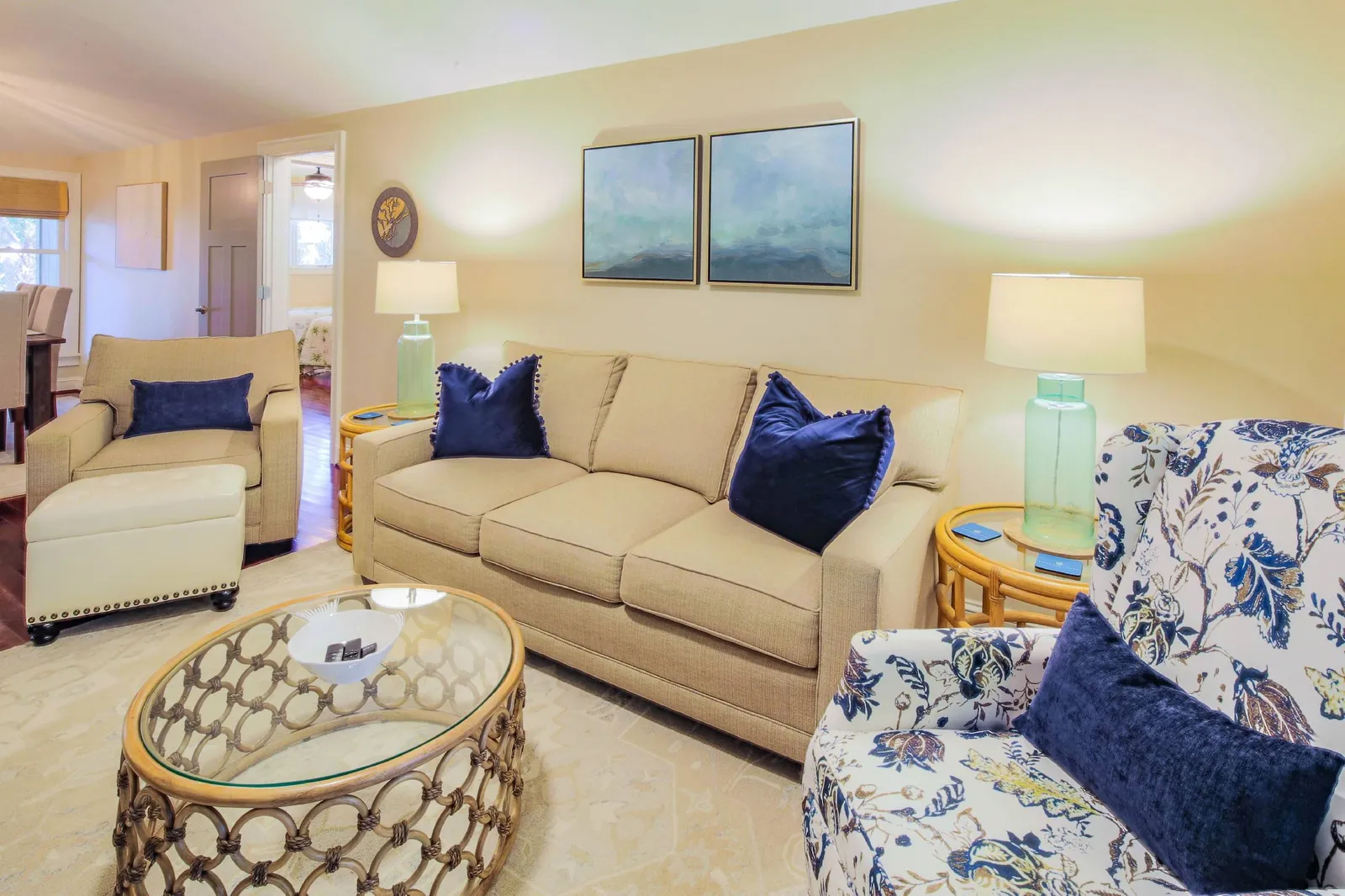 The living room features a sofa, two arm chairs and tables.