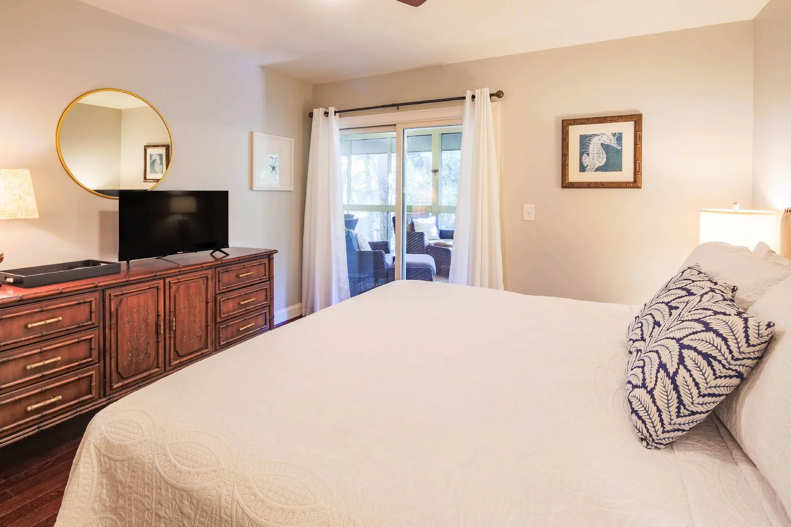 The primary suite also features a dresser, smart TV and sliding door access to the screend porch.