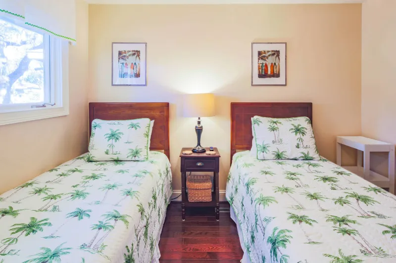 There are two night stands and a reading lamp in the twin bedroom.