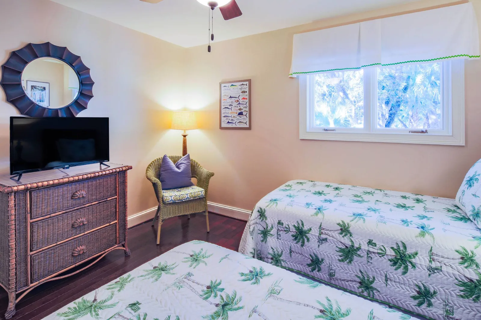 The twin bedroom also features a dresser with smart TV, chair, floor lamp and ceiling fan.