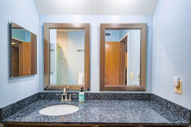 The bathroom features a spacious vanity with one sink, two mirrors and a medicine cabinet.