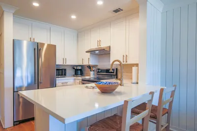 The kitchen features stainless steel appliances, white cabinetry and a tiled backsplash.
